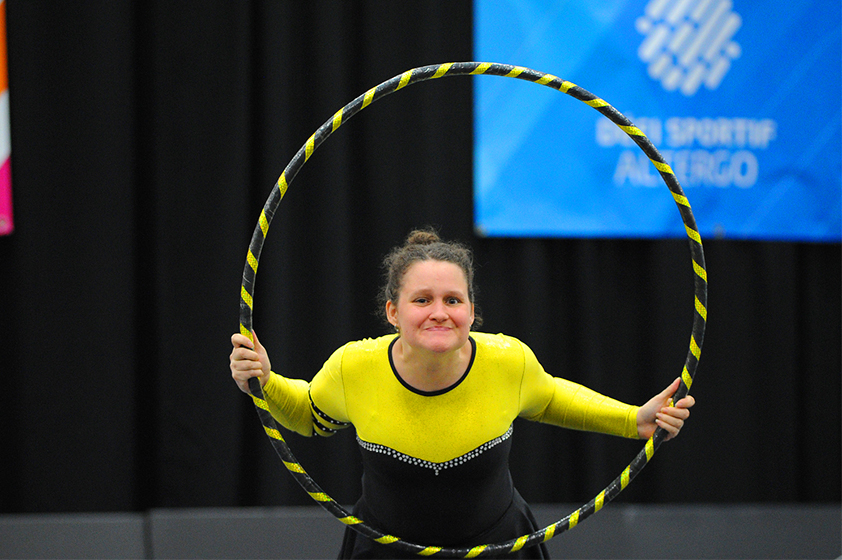 An athlete holding a hoop around her upper body.
