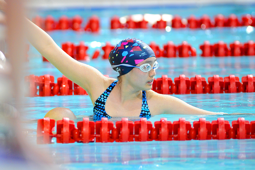 Une athlète en position de départ dans une piscine pendant une compétition de natation.