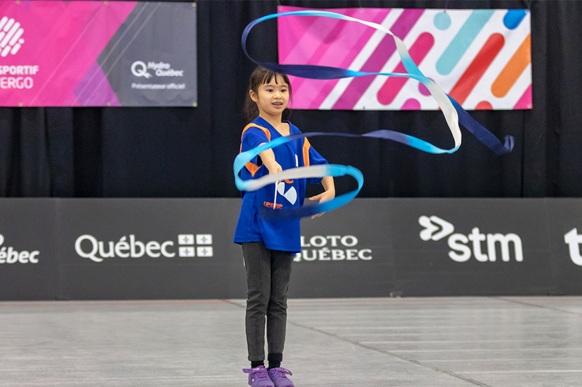 An athelete waving a ribbon during a rhythmic gymnastics event. 