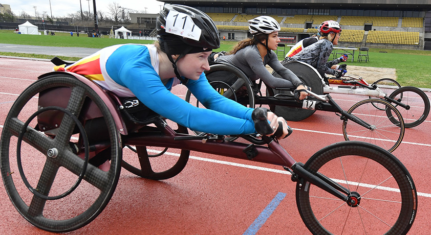 Des athlètes en fauteuil roulant sur la ligne de départ d'une course sur piste.