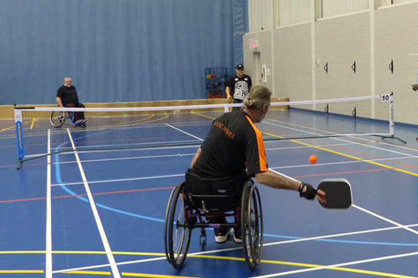 Un athlète en fauteuil roulant se prépare à mettre un panier pendant que son adversaire tente de récupérer le ballon.
