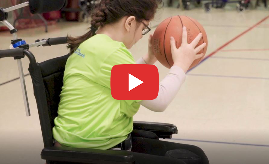 Une jeune fille en fauteuil roulant dribble avec un ballon de basketball.