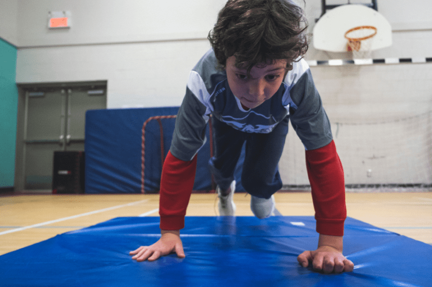 Un jeune garçon est en train de se positionner pour faire la planche durant une épreuve de CrossFit.
