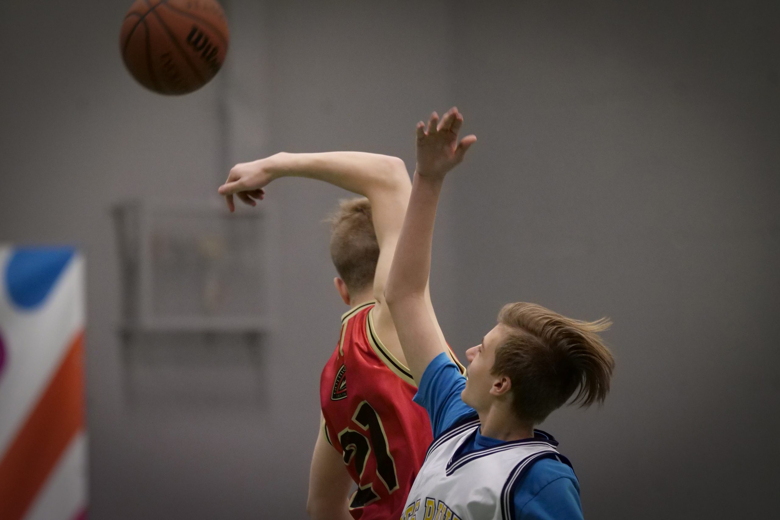 Description de l'image : Au centre, deux jeunes joueurs de basketball se disputent le ballon, qui est dans les airs.