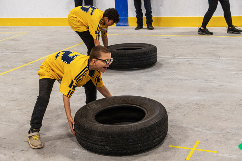 Deux garçons s'apprêtent à tourner un pneu lors d'une épreuve de CrossFit.