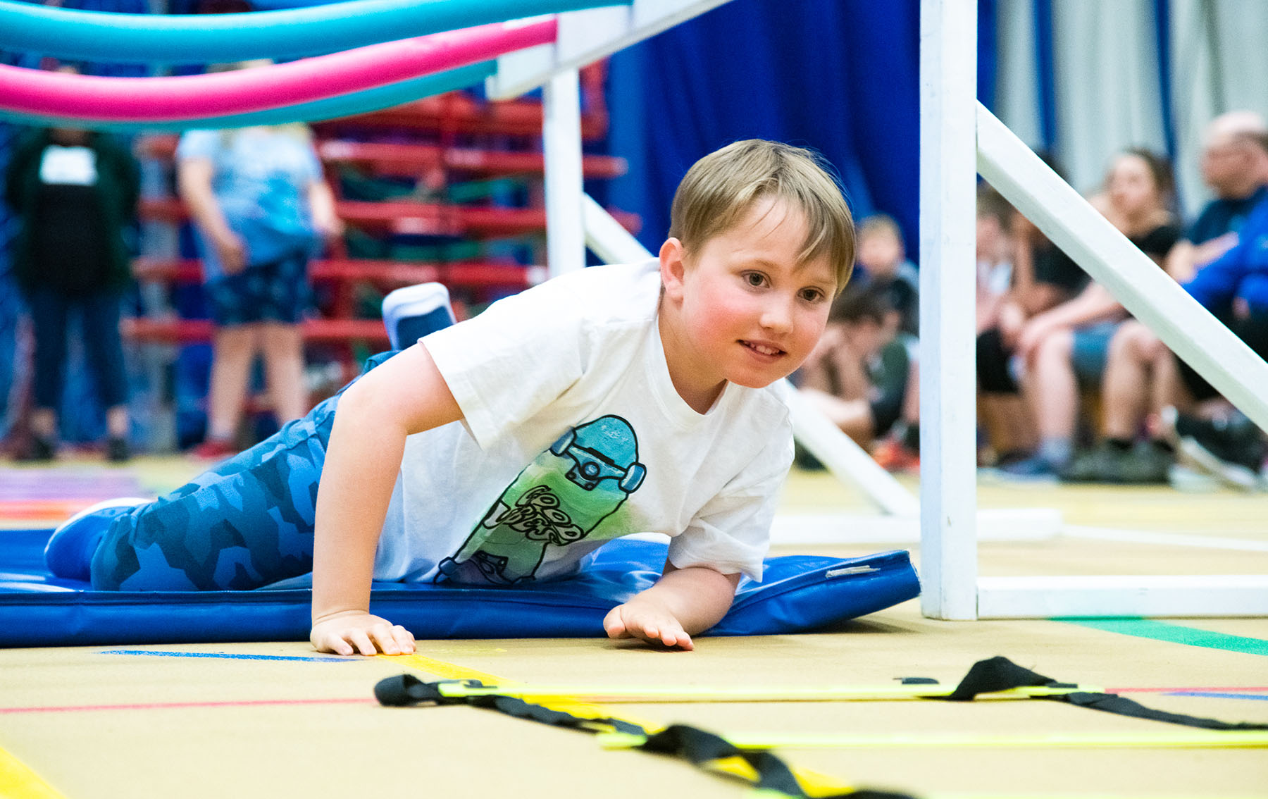 Un garçon rampe sur un tapis bleu pendant l'épreuve de circuit fonctionnel.